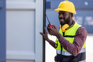 Foreman 'ın elinde telsiz var. Konteyner kargo alanında çalışıyor. Açık hava için el bilgisayarı telsizi.