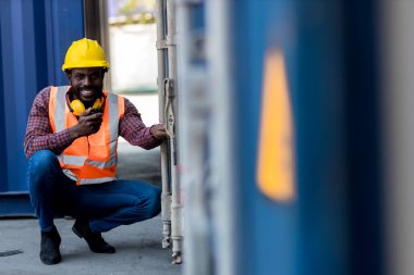 Foreman 'ın elinde telsiz var. Konteyner kargo alanında çalışıyor. Açık hava için el bilgisayarı telsizi.