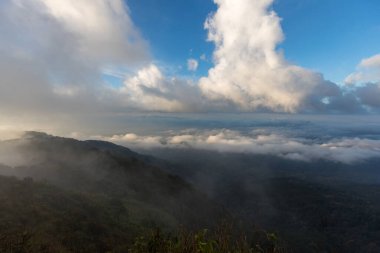 Beyaz sis ya da bulutlu manzaralı hava manzarası. Bulutlar arasında uçuyor ve dağın tepelerinde sis var..