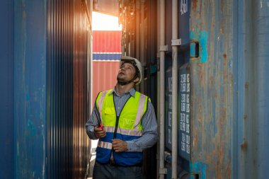 Konteyner kargo alanında çalışan profesyonel ustabaşı konteynırdaki malları kontrol ediyor. İşçiler denetleme ve kontrol için konteynırları açıyorlar..