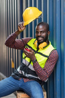 Foreman 'ın elinde telsiz var. Konteyner kargo alanında çalışıyor. Açık hava için el bilgisayarı telsizi.