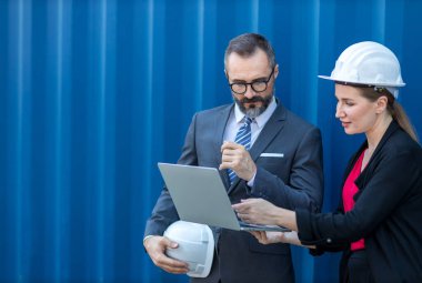 İş adamı ve sekreteri konteyner kargo alanında çalışıyor. Konteynırdaki malları kontrol ediyorlar. Menajer ve müşteri konteynırları kontrol ediyor. Lojistik ve nakliye.