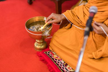 Buda keşişi şamdanı kutsal su kabının üstünde tutuyor. Din töreni. Budist kutsal suyu.. 