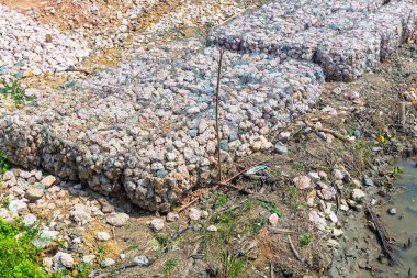 Taş duvarlar, kıyı aşınmasından korunma. Metal ağdaki taşlar. Çelik tel örgü sepetinden yapılmış Gabion duvarı. Nehir kıyısında granit kayalarla dolu çelik bir Gabion..