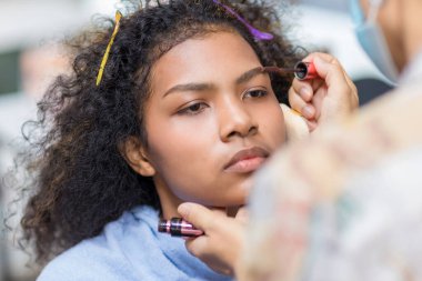 Stilist, kaşlarını fırçalayan siyah kadın kaşlarına makyaj yapıyor. Makyöz stilisti. Kaşlarını fırçayla fırçala. Modeli doğal makyaj yapar.