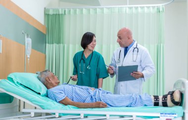 Doktor, koğuştaki hastayı ziyaret ediyor. Hastanede yatan adam doktorunu kontrol ederken yatakta yatıyor. Hastane odasında erkek hastayı muayene eden bir doktor..