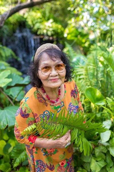 Baharda ya da yaz orman parkında mutlu bir kadın. Yeşil ormanda duran Asyalı Yaşlılar Gözlük Giyiyor