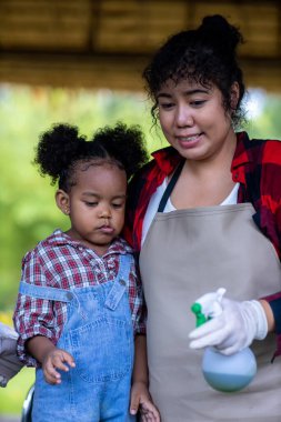 Sebze yetiştiriciliği ve bahçe işleriyle uğraşan bir kadın ve küçük bir kız. Anne ve kızı, insanların aileleri için bahçeye sebze ekiyor.