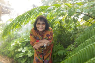 Baharda ya da yaz orman parkında mutlu bir kadın. Yeşil ormanda duran Asyalı Yaşlılar Gözlük Giyiyor