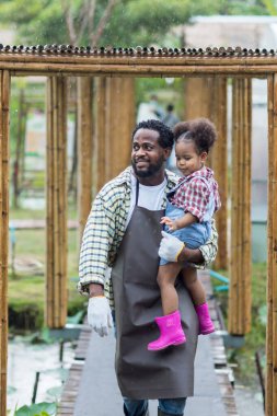 Babası sakallı, kızını kollarına almış yağmurda ona sevgiyle bakıyor. Mutlu bir baba kızını kucaklıyor ve gülüyor..