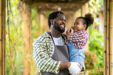 Babası sakallı, kızını kollarına almış yağmurda ona sevgiyle bakıyor. Mutlu bir baba kızını kucaklıyor ve gülüyor..