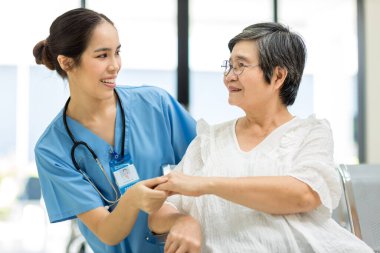 Hemşire hastane koğuşundaki yaşlı hastayla ilgileniyor. Yaşlı bir kadın hastanede oturuyor. Muayene için hastanedeki kıdemli kadın.