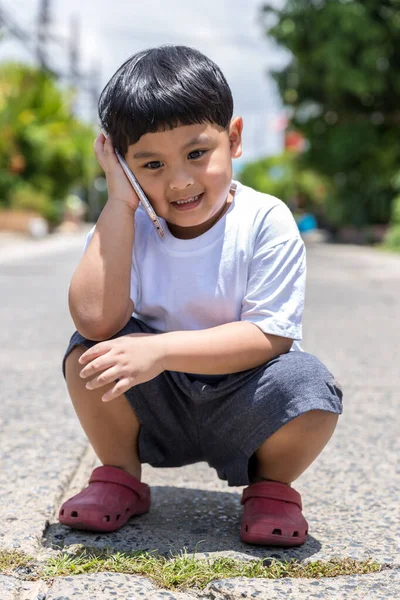 Little boy using mobile and call talking on the phone on street.