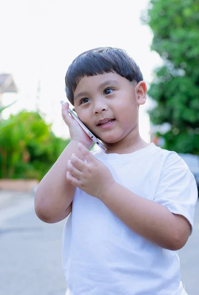 Little boy using mobile and call talking on the phone on street.