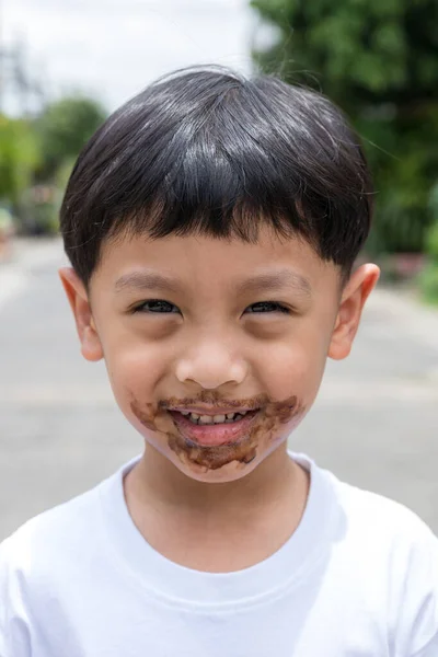 Child face messy and dirty by chocolate ice cream. Child with face covered in chocolate.