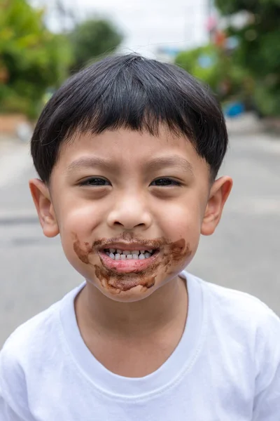 Child face messy and dirty by chocolate ice cream. Child with face covered in chocolate.