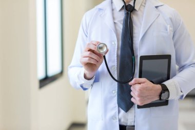 Steteskopu hastanede tutan doktor. Üniformalı, steteskop tutan dost canlısı bir erkek doktor. Elinde steteskop muayenesi olan sabahlıklı bir doktor..