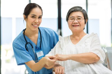 Hemşire hastane koğuşundaki yaşlı hastayla ilgileniyor. Yaşlı bir kadın hastanede oturuyor. Muayene için hastanedeki kıdemli kadın.