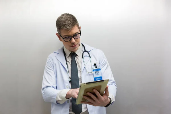 Doctor holding tablet at hospital. Friendly male doctor dressed in uniform holding tablet.