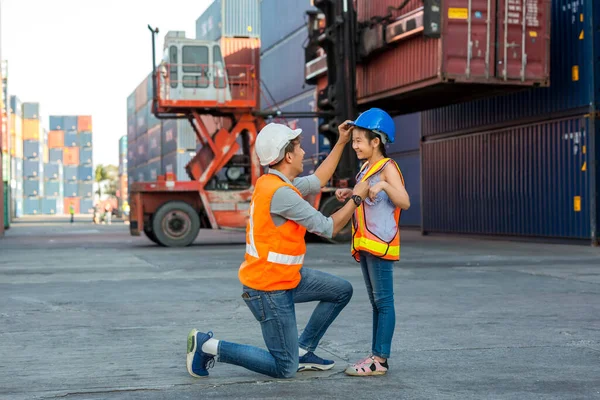 Father and little daughter wearing a safety helmet at Container cargo site. Business heir concept. Happy father and daughter wearing safety helmet work site. Business heir concept