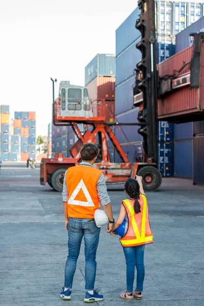 Father and little daughter wearing a safety helmet at Container cargo site. Business heir concept. Happy father and daughter wearing safety helmet work site. Business heir concept