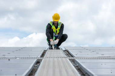 Çatıda çalışan mühendis güneş paneli kuruyor. Mühendis ya da işçi iş binasının çatısındaki güneş panelleri ya da güneş pilleri üzerinde çalışır.