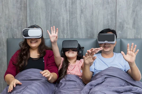 Family time using VR glasses together on bed at home for gaming or learning.