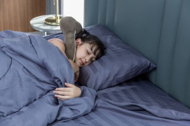 Yatakta uyuyan kız. Asyalı çocuk uyuyor ve tatlı rüyalar yatıyor rahat bir yatak odasında.