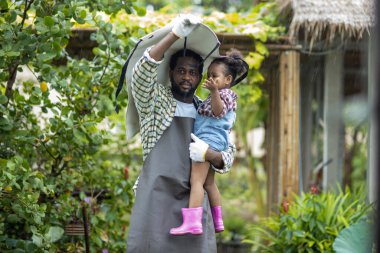 Babası sakallı, kızını kollarına almış yağmurda ona sevgiyle bakıyor. Mutlu bir baba kızını kucaklıyor ve gülüyor..