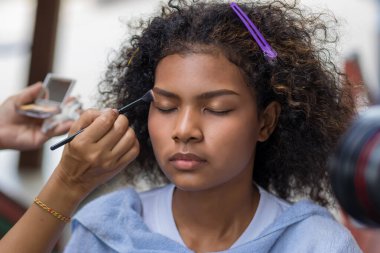 Stilist, kaşlarını fırçalayan siyah kadın kaşlarına makyaj yapıyor. Makyöz stilisti. Kaşlarını fırçayla fırçala. Modeli doğal makyaj yapar.