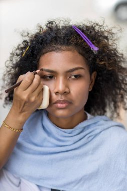 Stilist, kaşlarını fırçalayan siyah kadın kaşlarına makyaj yapıyor. Makyöz stilisti. Kaşlarını fırçayla fırçala. Modeli doğal makyaj yapar.