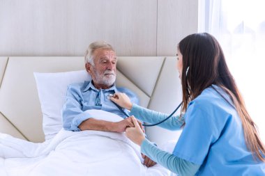 Bakıcı hemşire steteskop kullanarak kıdemli hastayı kontrol ediyor. Hemşire steteskopa yardım ediyor. Evde kalp atışlarını kontrol ediyor.