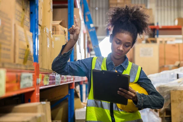 african american female worker in uniform working with clipboard in warehouse