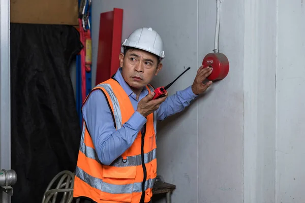 Foreman or worker pushing fire alarm on the wall. A fire! or Emergency case at the factory building. Emergency of Fire alarm or alert or bell warning equipment