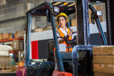 smiling delivery worker with forklift in uniform standing in warehouse