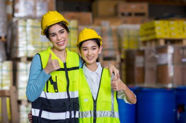 portrait of female worker in protective uniform and yellow vest standing in factory