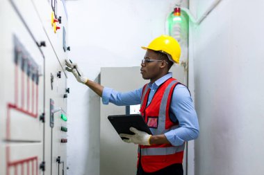 Kontrol odasında çalışan elektrik mühendisi. Elektrik mühendisi kontrol odasındaki güç dağıtım dolabını kontrol ediyor.