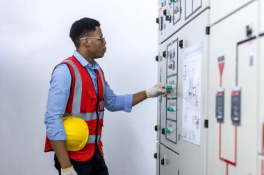 Kontrol odasında çalışan elektrik mühendisi. Elektrik mühendisi kontrol odasındaki güç dağıtım dolabını kontrol ediyor.