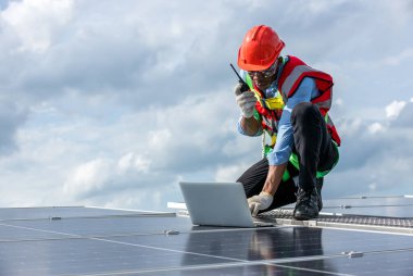 Çatıda çalışan mühendis güneş paneli kuruyor. Mühendis ya da işçi iş binasının çatısındaki güneş panelleri ya da güneş pilleri üzerinde çalışır.