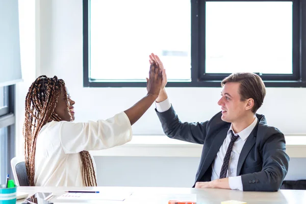 businesswoman and businessman giving hi five touching hands. Coworkers cooperating and working together at office meeting, teamwork concept. Business woman and Business man meeting in modern office.