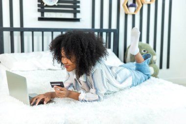 Young woman consumer holding credit card and laptop buying online at home. Woman shipping online with credit card in hand. Women using laptop technology paying credit card shopping online