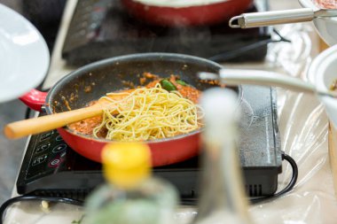 Spagetti pişirme konsepti. Tavada makarna. Fresco Pasta Pişiriyorum. İtalyan mutfağı, pişirilmiş İtalyan spagettisi tavada sıcak bolonez sosuna konuyor.