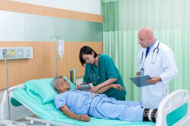 Doktor, koğuştaki hastayı ziyaret ediyor. Hastanede yatan adam doktorunu kontrol ederken yatakta yatıyor. Hastane odasında erkek hastayı muayene eden bir doktor..