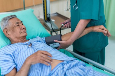 Doktor, koğuştaki hastayı ziyaret ediyor. Hastanede yatan adam doktorunu kontrol ederken yatakta yatıyor. Hastane odasında erkek hastayı muayene eden bir doktor..