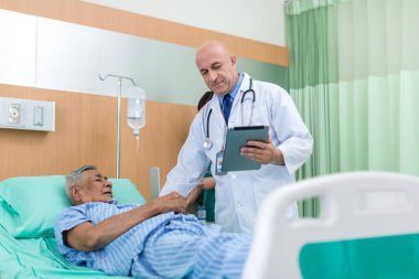 Doktor, koğuştaki hastayı ziyaret ediyor. Hastanede yatan adam doktorunu kontrol ederken yatakta yatıyor. Hastane odasında erkek hastayı muayene eden bir doktor..