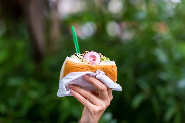 The scoops of ice cream are put in the bread. Ice cream with bread Thai street food. A soft bread topped with scoop of ice cream on Hand.