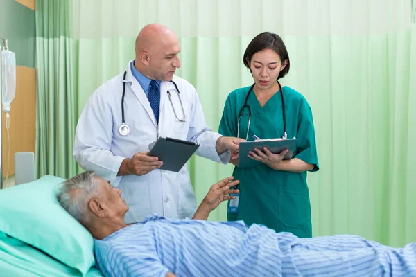 Doctor Visiting man Patient On Ward. Hospitalized man lying in bed while doctor checking his. physician examining male patient in hospital room.