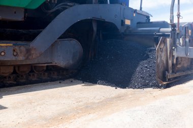 Paver machine on a new asphalt road surface. Laying of a new asphalt pavement on a city street with the use of machinery.