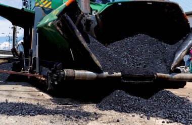 Paver machine on a new asphalt road surface. Laying of a new asphalt pavement on a city street with the use of machinery.