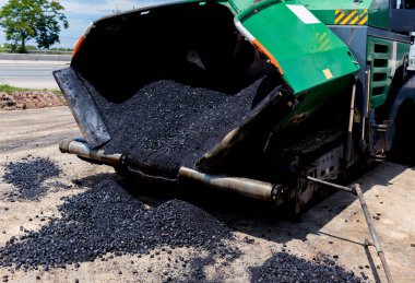 Paver machine on a new asphalt road surface. Laying of a new asphalt pavement on a city street with the use of machinery.